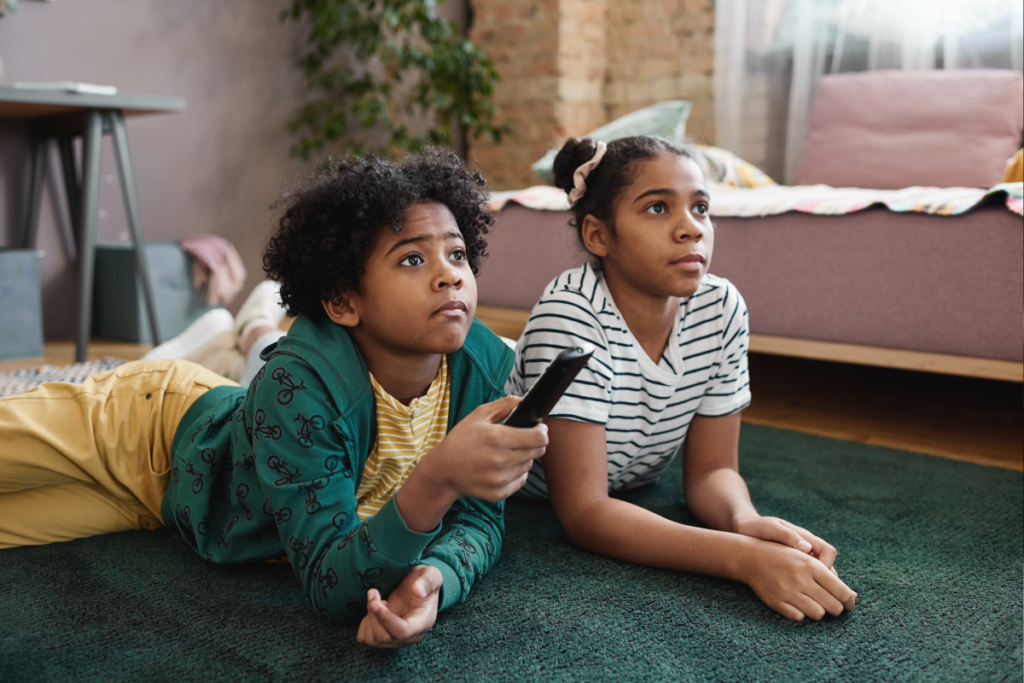 two kids sitting on the floor watching tv