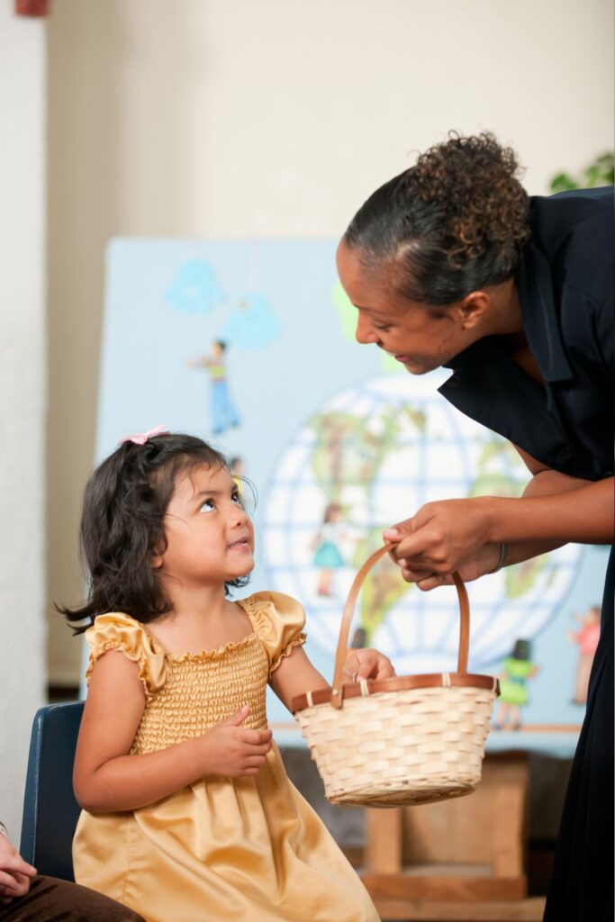 a young girl reaching into a basket to pull out a memory verse from a teacher